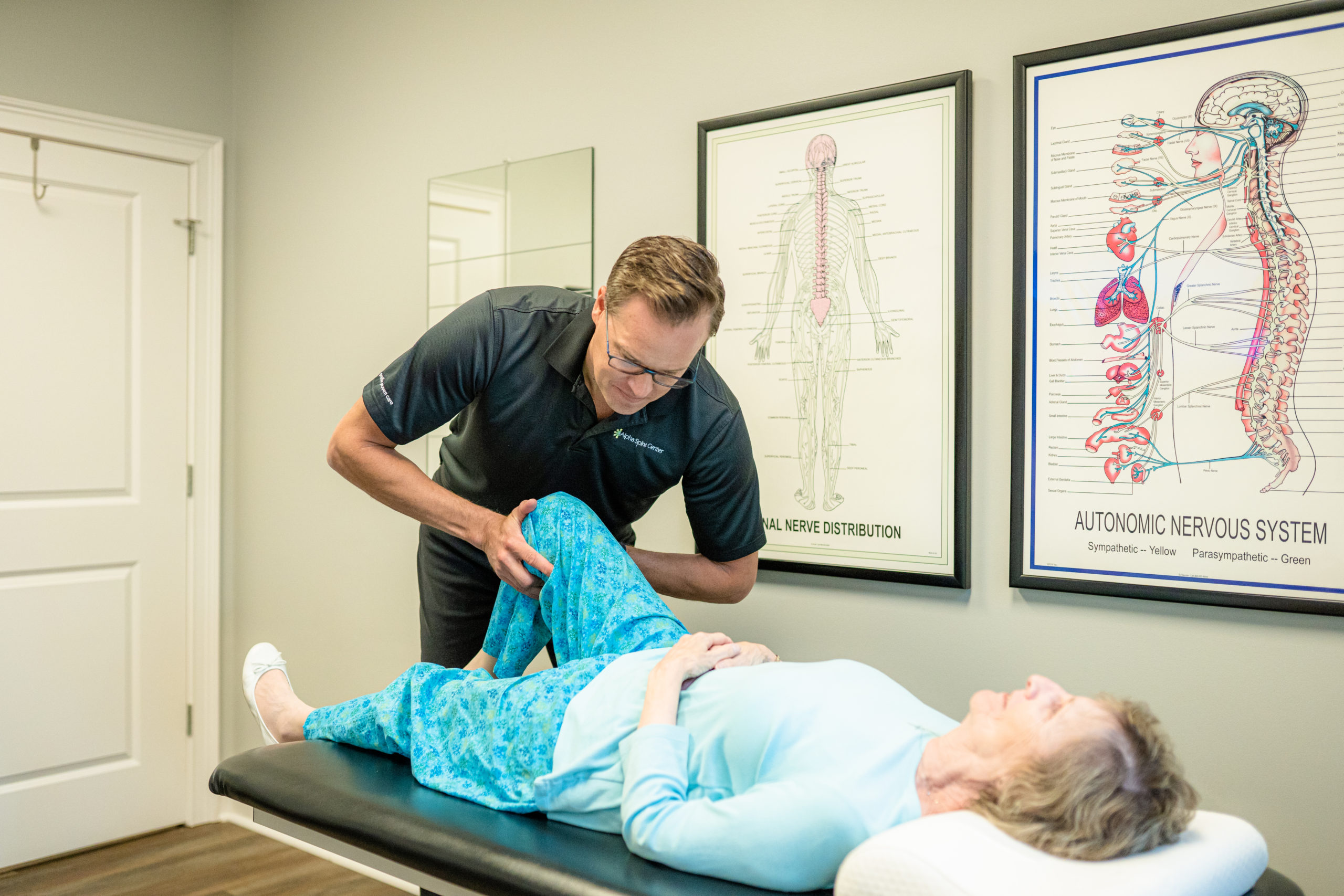 Dr. Bryan Salminen evaluating a patient’s bent knee at Alpha Spine Center.