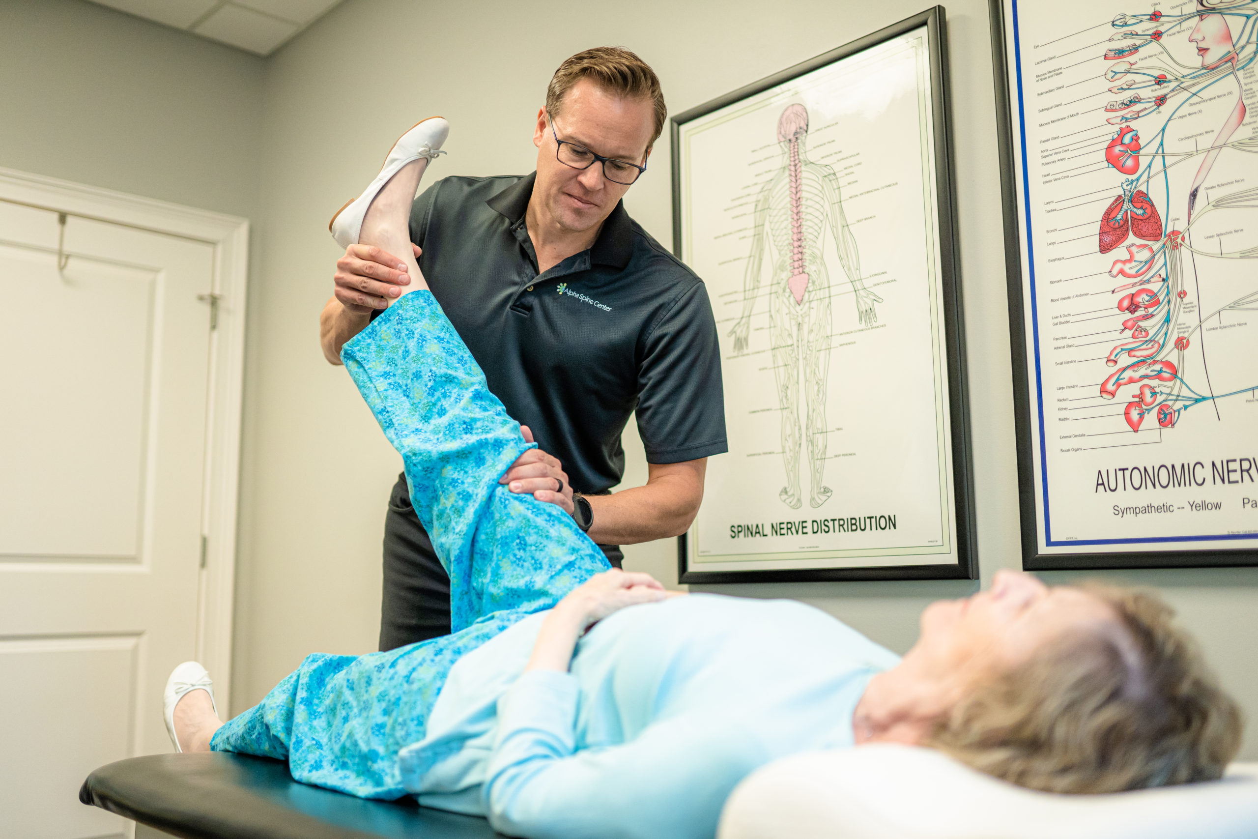 Dr. Bryan Salminen assessing a patient’s hip and leg movement at Alpha Spine Center.