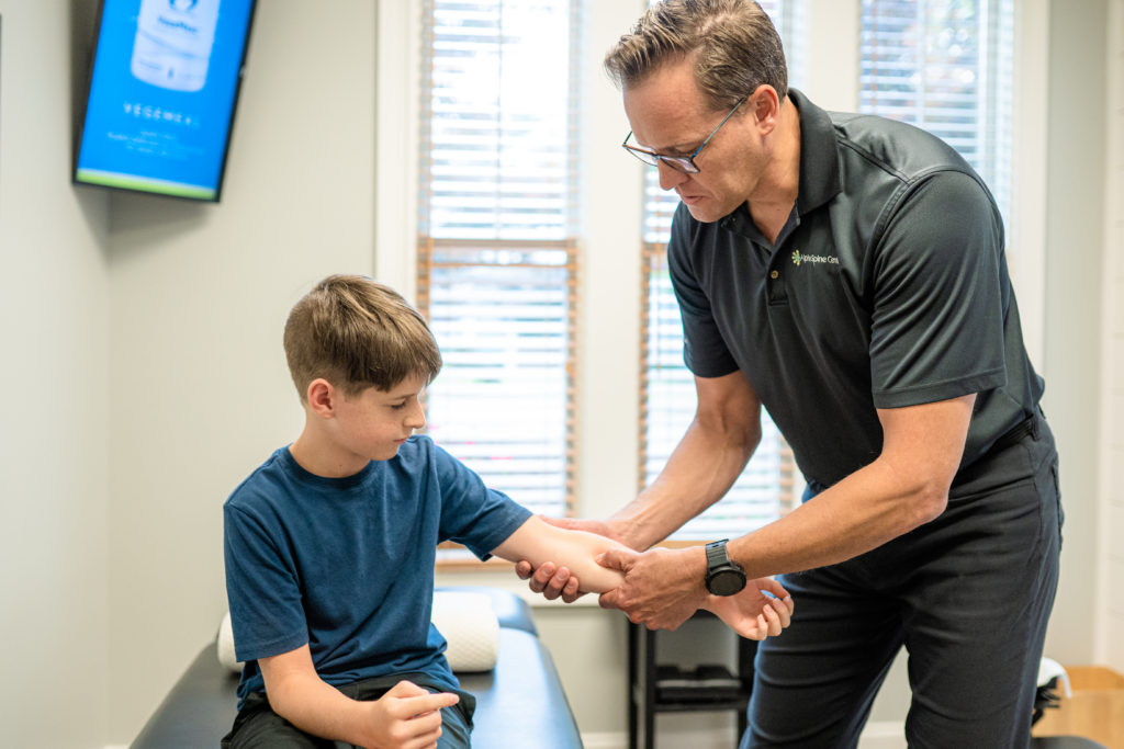 Dr. Bryan Salminen evaluating a child’s elbow and arm at Alpha Spine Center.