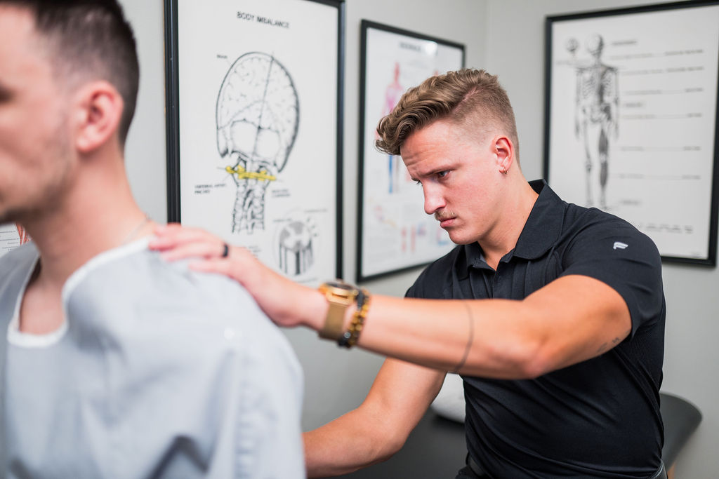 Dr. Andrew “Drew” Salminen examining a patient’s shoulders and posture at Alpha Spine Center in Milton, Georgia.