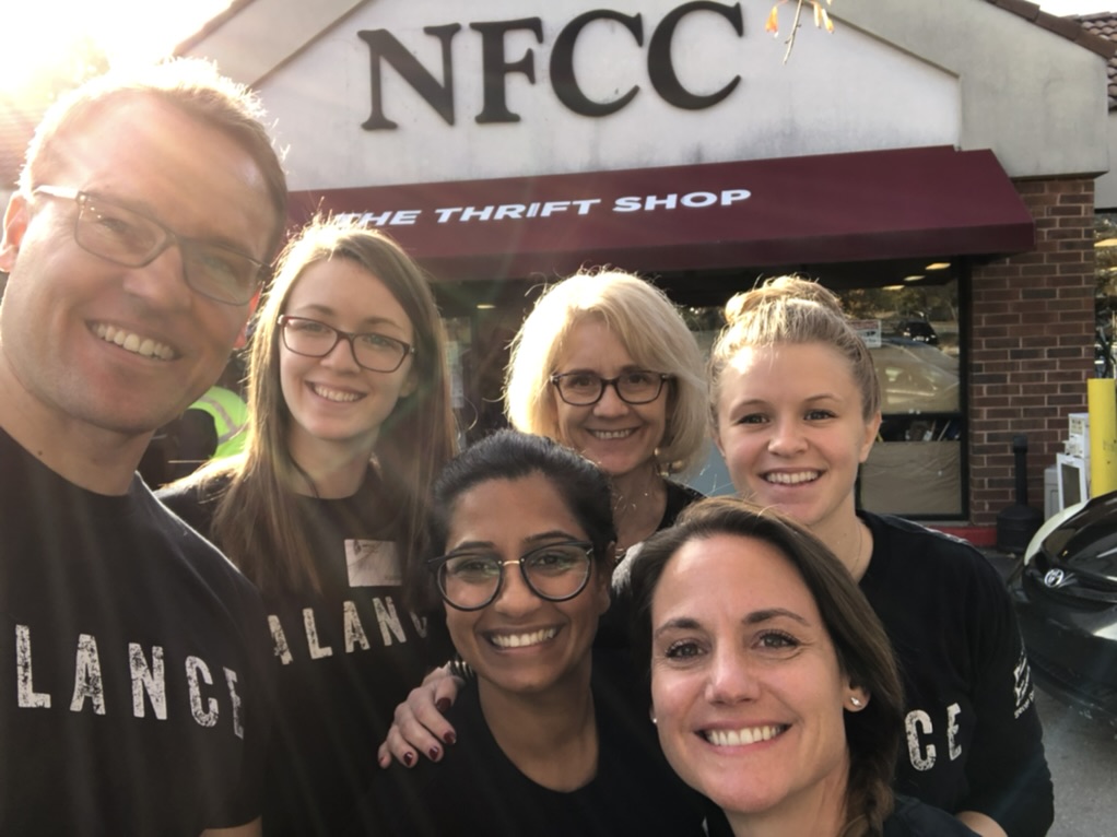 Dr. Bryan and Alpha Spine Center team members smiling outside the NFCC Thrift Shop