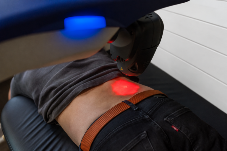 Close-up of the M6 laser positioned over a patient’s back; office background digitally edited.